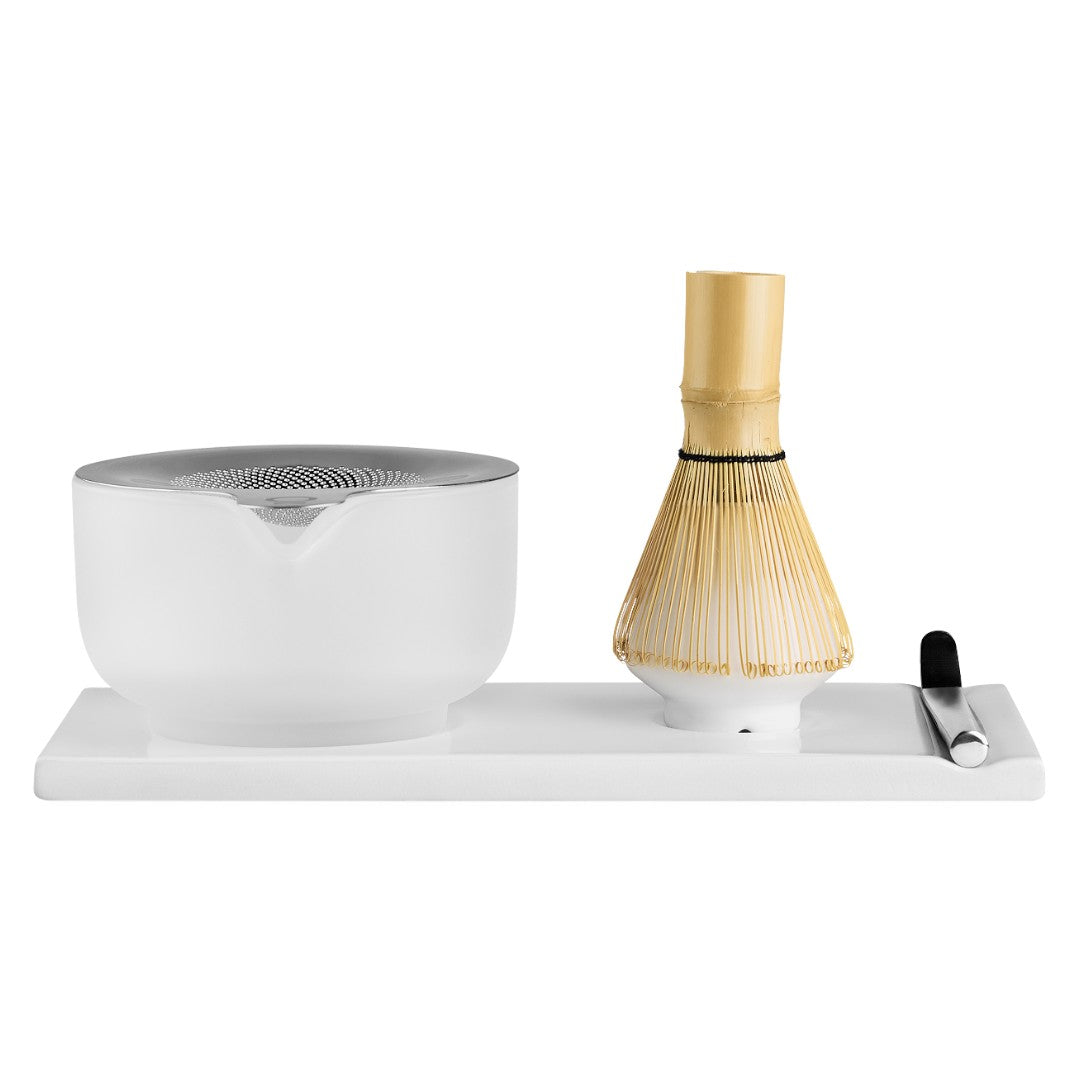 Fellow Japanese matcha tea preparation set on a white rectangular base, featuring a frosted glass chashaku bowl, a bamboo whisk, and a metal scoop, photographed against a solid white background.